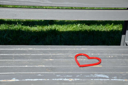 Red heart figure on wooden park benchの写真素材