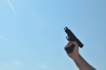 Replica of a gun in a hand, directed to the sky, in position when there is no more bulletsの写真素材