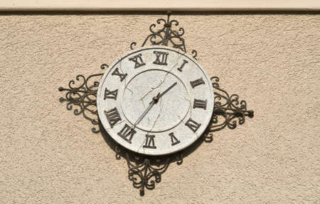 Vintage clock with Roman numbers - showing twenty-five to two - on stone wallの写真素材