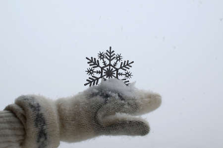 Winter wool glove with snowflake as decoration and with just fallen fresh snow