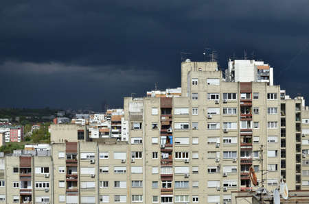 Stormy dark blue sky above a quarter of tall residential buildingsの写真素材