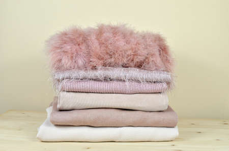 Pile of pink garments of different materials - feather, cotton, woolen, corduroy velvet - on wooden shelfの写真素材