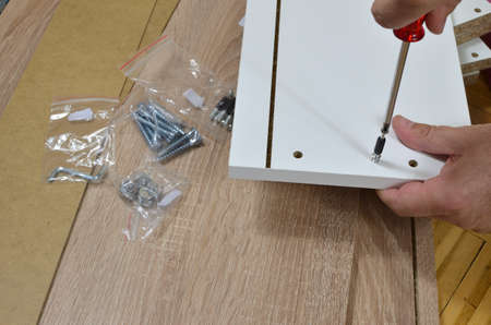 Screwing a wood screw in a drawer element using a screwdriverの写真素材