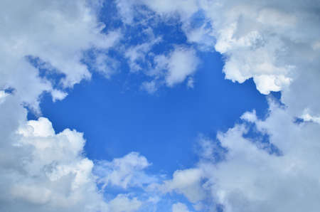 Blue sky and white fluffy clouds with a space for text in a central part - suitable for a backgroundの写真素材