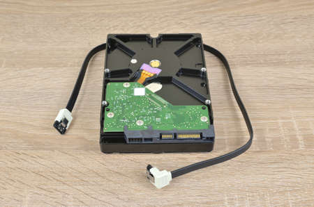 Hard disk and its SATA cable on a wooden surfaceの写真素材