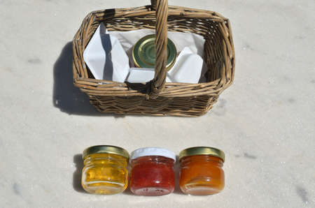Small jars with organic fruit jam and honey for breakfast on a garden table on sunny dayの写真素材