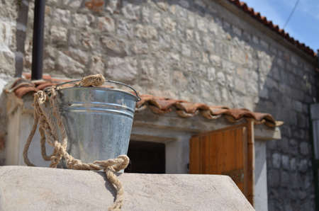 Silver tin pail in front of an old Mediterranean houseの写真素材