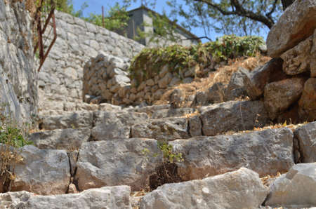 Rustic village stone stairs abandoned and overgrown with dry grass in summertime