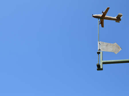 Hand made weather vane with an arrow, small plane and clear blue skyの写真素材
