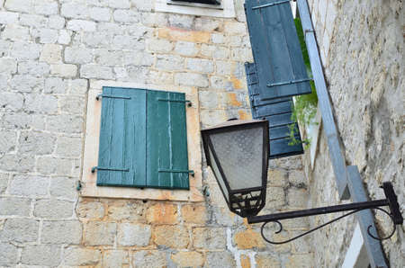 Closed window with wooden blinds of a coastal stone houseの写真素材