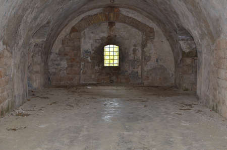 Prison cell with a window covered with bars in an abandoned old fortressの写真素材