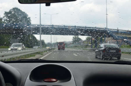 Driving a car with a wet front glass on a highway with a viaduct in front ofの写真素材