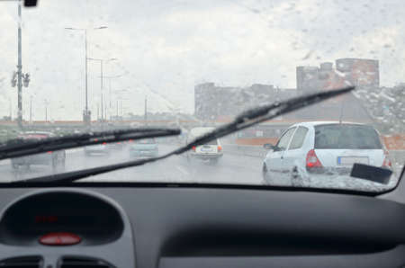 Driving on a road with other vehicles in his direction on a rainy dayの写真素材