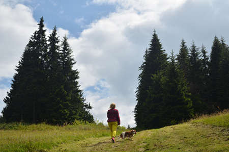 Woman dressed in royal stewart hiking with her dog - Cavalier King Charles Spaniel - on mountain pathの写真素材