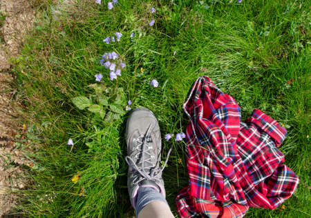 Leg in trekking shoe stepping on mountain field with wild flowersの写真素材