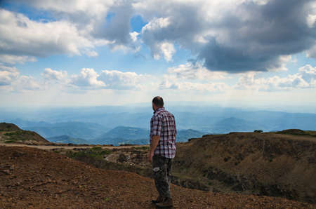 Man dressed for hiking is walking on top of Kopaonik mountain, Serbia and watching landscapeの写真素材
