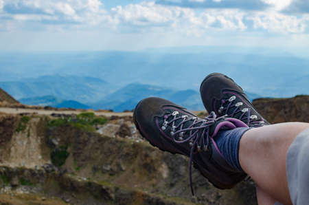 Legs in trekking shoes with mountain landscape in a backgroundの写真素材
