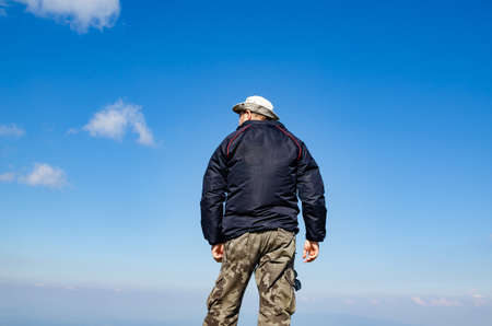 Man dressed for hiking standing against blue skyの写真素材