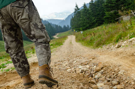 Hiker's legs while walking on a path leading through hillsの写真素材
