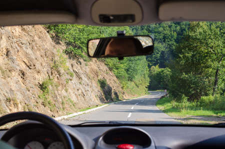 Driving on a road that goes through a mountain countryside in summertime