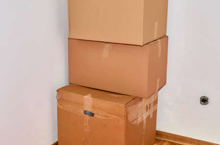Three cardboard moving boxes in a corner of a room