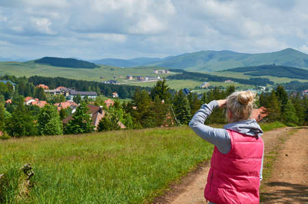 Blond woman watching and enjoying a mountain landscape in springtimeの写真素材