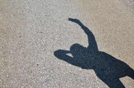 Shadow on an asphalt background of a woman posing to take a selfie