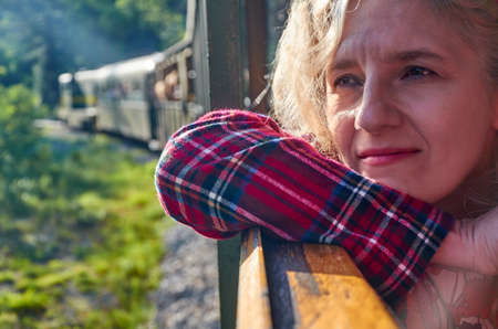 Woman leaned out off a train window and watching out while travelingの写真素材