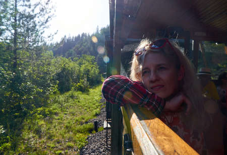 Woman leaned out off a train window and watching out while traveling