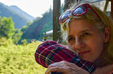 Woman dressed in a royal stewart red tartan shirt leaned out off a train windowの写真素材