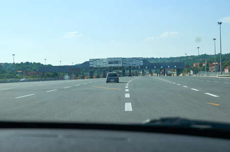 Car on a highway approaching a pay toll during a dayの写真素材