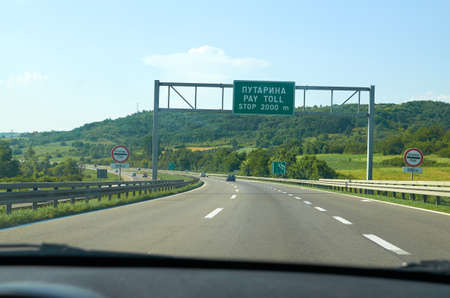 Traffic and traffic signs on a highway announcing a pay toll written in Serbian