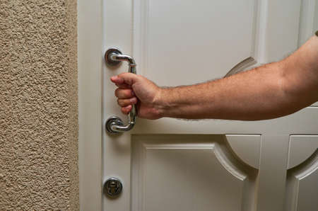 Close-up of a man's hand holding a door handle