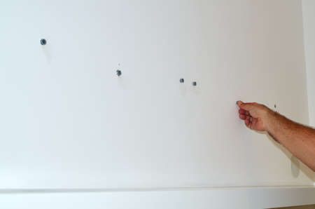 Inserting plastic screw plugs in a white wall