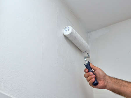 Man painting wall in white color with a rollerの写真素材