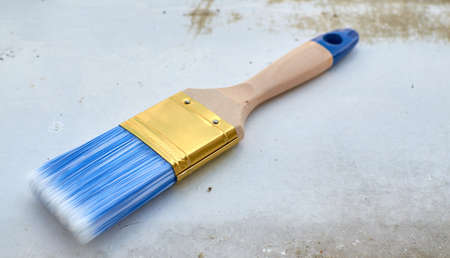 New wooden brush for painting with blue hairs on an old metal surface