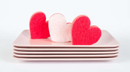 Pink plates and red and pink dish, kitchen sponges in heart shapeの写真素材