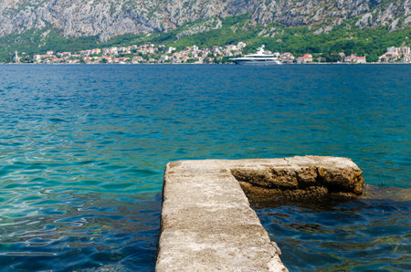 Sea dock, yacht and vivid blue sea with a small sea town in backgroundの写真素材