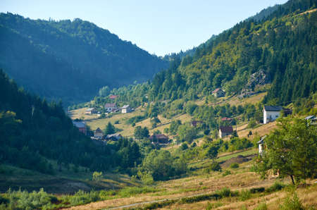 Mountain village surrounded with pines beneath blue skyの写真素材