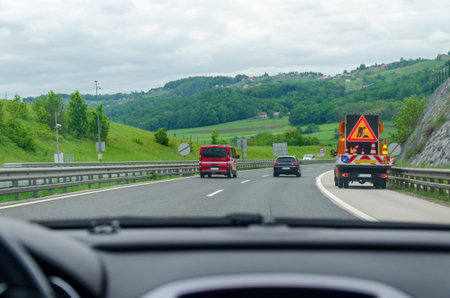 Driving on a highway passing by a road maintenance vehicle - view from a car windshield