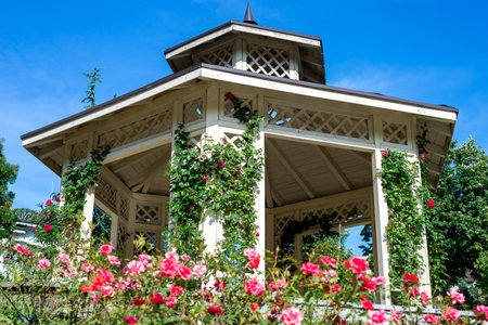 Elegant gazebo surrounded with lush park flowers in summertimeの写真素材