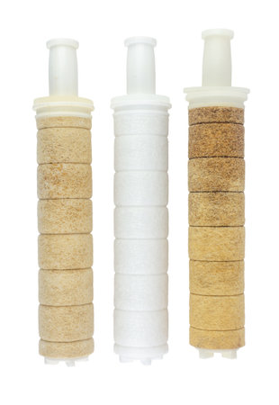 Side-by-side on a white background, two heavily soiled and worn water filters are positioned next to...