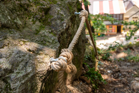 Close-up of a thick, knotted rope attached to a side surface and serving as a handrail for walkers