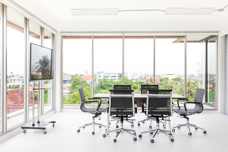 Group of conference table and chairs in white and wide office with television screen without anyone in roomの写真素材