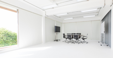 Group of conference table and chairs in white and wide office with television screen without anyone in roomの写真素材