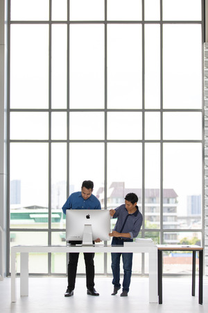 BANGKOK, THAILAND - MAY 05, 2018: Asian businessmen unbox and setting up new iMac computer in office. Apple computer is one of the most popular equipment in modern office.のeditorial素材
