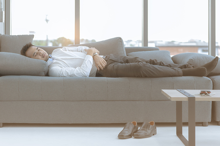 The young man was sleeping on a large sofa comfortably.の写真素材
