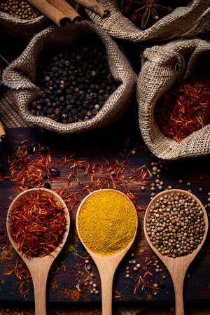 Coloful various spice and herbs in wood spoon on natural texture burned wood plate.の写真素材