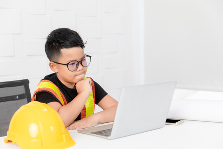 Kid engineer action look like thinking to see something notebook on the desk. Concept of learning to build a career in the future.の写真素材