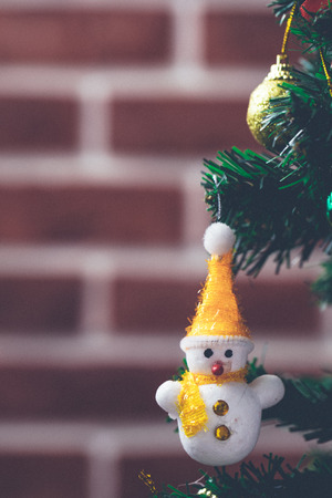 White snowman doll hanging on fake pine tree decorated in home. Concept for big festival merry christmas and happy new year.の写真素材